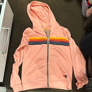 Light pink Aviator Nation zip up hoodie with multi colored stripes
